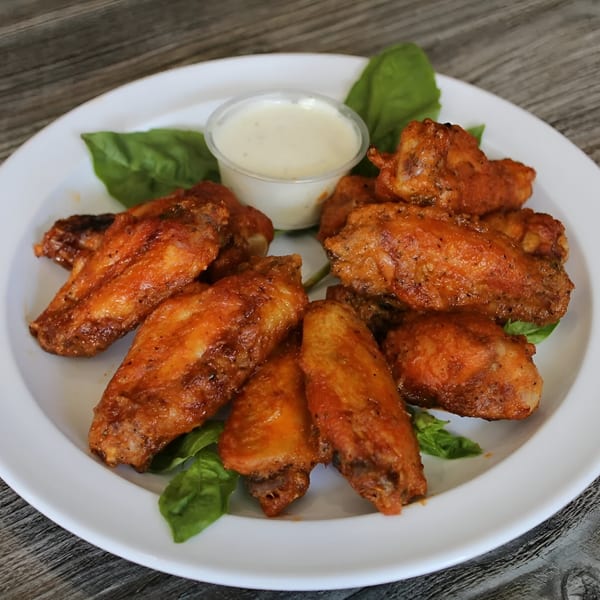 A plate of Canadian Pizza & Grill's spicy chicken wings with a side of ranch dressing.