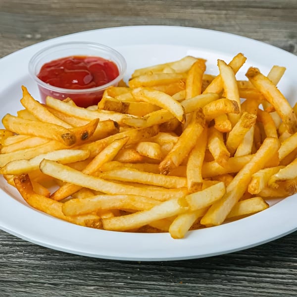 A white plate filled with golden french fries and a small cup of ketchup.