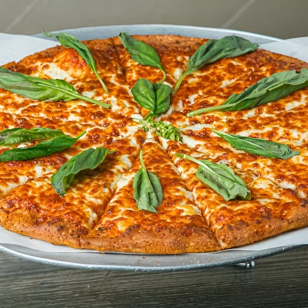 A freshly baked Canadian Pizza & Grill cheese pizza, sliced and garnished with basil leaves.